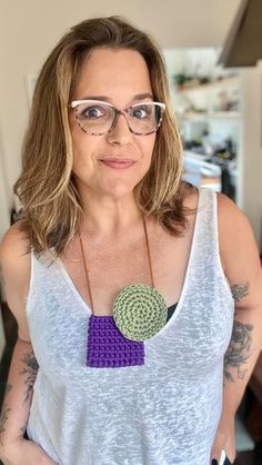 a woman wearing glasses and a necklace with a crocheted disc on it's neck