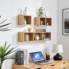 a laptop computer sitting on top of a wooden desk next to a potted plant