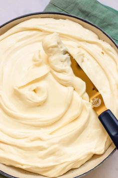 a pan filled with white frosting next to a blue spatula