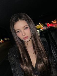 a woman with long hair sitting in the back seat of a car looking at the camera