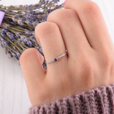 a woman's hand with a ring on it next to lavender flowers and a purple ribbon