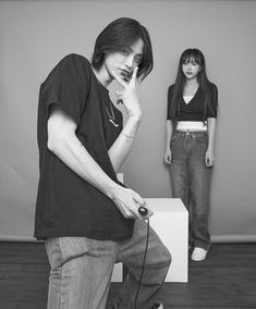 two young people standing in front of a white box and one is holding a cell phone