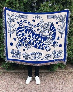 a woman holding up a blue and white quilt