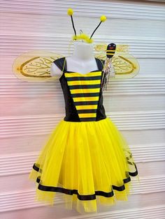 a dress made to look like a bee with yellow and black stripes is hanging on a wall