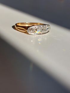 two gold rings with diamonds on them sitting on a white surface, in the sunlight