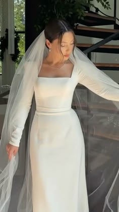 a woman in a white dress and veil is walking down the stairs with her hands on her hips