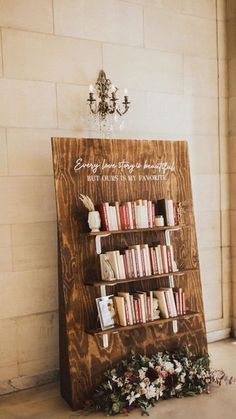 a wooden book shelf with books on it next to a chandelier and flowers