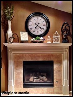 a fireplace with a clock above it and other decorations on the mantels below