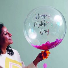 a woman holding a large bubble balloon with flowers on it that says happy mother's day