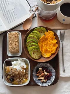 an open book on a table with food and drinks in bowls, along with a cup of coffee