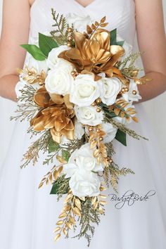 a bride holding a bouquet of white and gold flowers