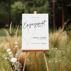 an easel with a sign that says engagement party on it and flowers in the foreground