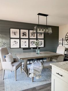 a dining room table with chairs and pictures on the wall