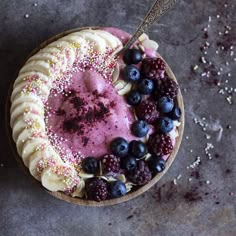 a bowl filled with berries, bananas and other toppings on top of a table