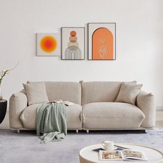 a living room with two pictures on the wall and a couch in front of it