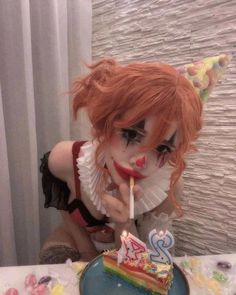 a doll with red hair and makeup holding a candle in front of a birthday cake