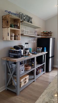 a kitchen with a refrigerator and shelves filled with wine glasses, cups, and other items