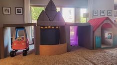 an indoor play area with toys in the shape of castles and cars on carpeted flooring