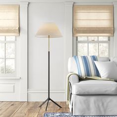 a living room with white walls and wooden floors, two lamps on either side of the couch