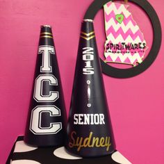 two party hats sitting on top of a table next to a pink wall and clock