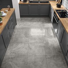 a kitchen with grey cabinets and wooden counter tops, gray tile flooring and white walls