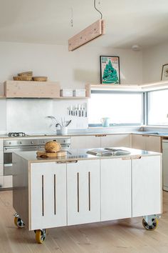 a kitchen with an island in the middle and lots of cupboards on wheels around it