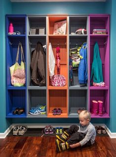 a little boy sitting on the floor in front of a colorful closet