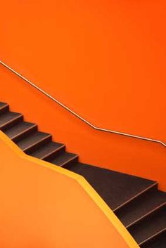 an orange wall with black stairs leading up to it