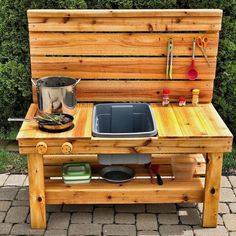 a wooden bench with a pot and pan on it's side, next to a garden table