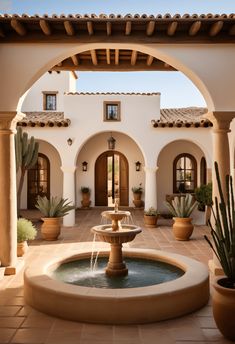 a fountain in the middle of a courtyard with potted cacti and succulents