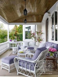 a porch with white wicker furniture and purple cushions on the couches is featured in this instagram