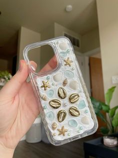 a person holding up a phone case with shells and starfish on it