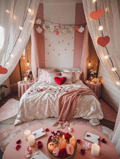 a bedroom decorated in pink and white with hearts hanging from the ceiling, candles on the bed