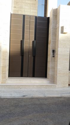 an entrance to a building with two brown doors and black shutters on the side