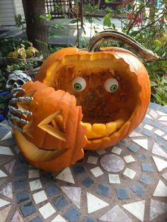 two carved pumpkins sitting on top of a mosaic table with eyes and hands in them