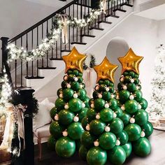 christmas tree made out of balloons and gold stars in front of the stairs with garlands