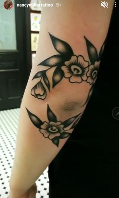 a woman's arm with black and white flowers on the left side of her body