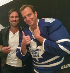 two men standing next to each other giving thumbs up