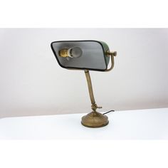 an antique brass desk lamp with a glass shade on the top and one bulb turned on