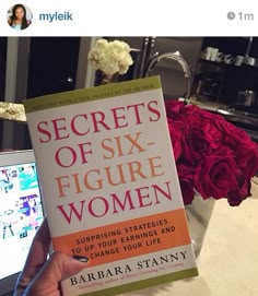 the book secrets of six figure women by barbara stanny is held up in front of a laptop