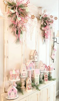 a white dresser topped with lots of pink and green christmas decorations on top of it