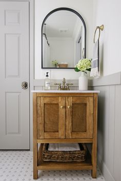 a bathroom with a sink, mirror and basket on the floor in front of it