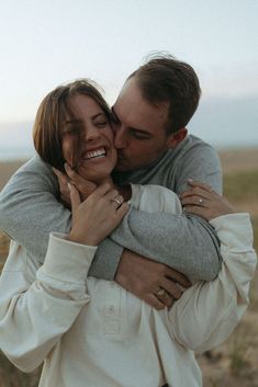 a man and woman embracing each other in an open field