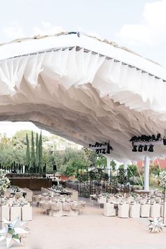 an outdoor event with tables and chairs under a white tent that has stars on it