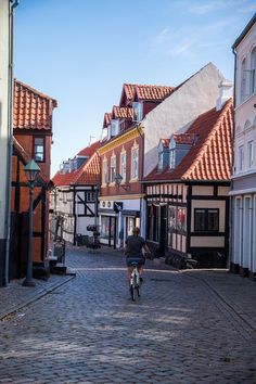 a person riding a bike down a cobblestone street in an old european town