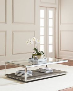 a living room with a glass coffee table and white rugs on the hardwood floor