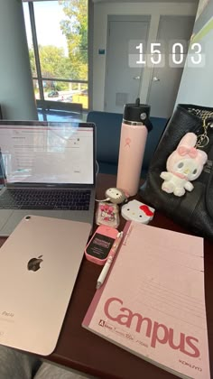 an open laptop computer sitting on top of a wooden desk next to a pink bag