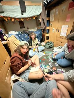 four people sitting on the floor in a dorm room