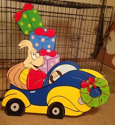 a cardboard car with presents in it on the floor next to a caged area