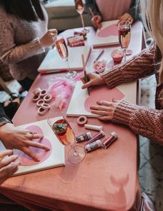 people sitting at a table with wine glasses and food on it, all holding their hands together